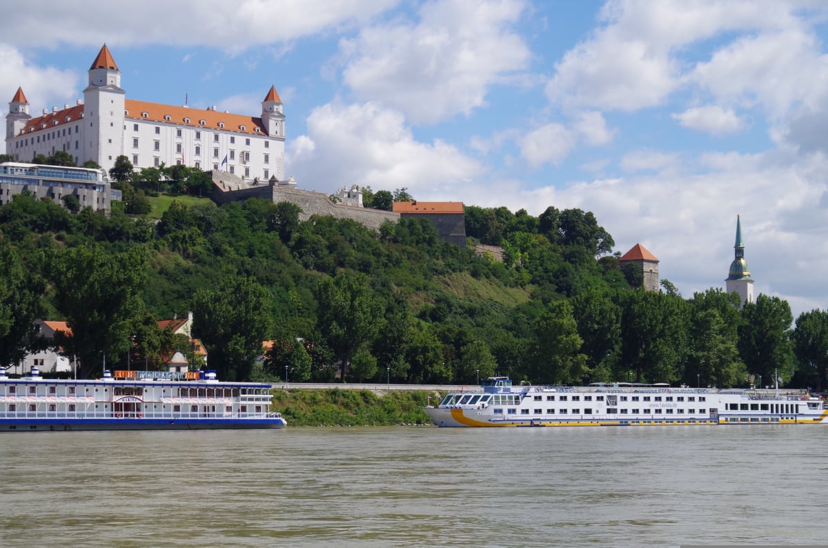 Bratislava Castle perched on a hilltop above the Danube River with a river cruise ship passing below